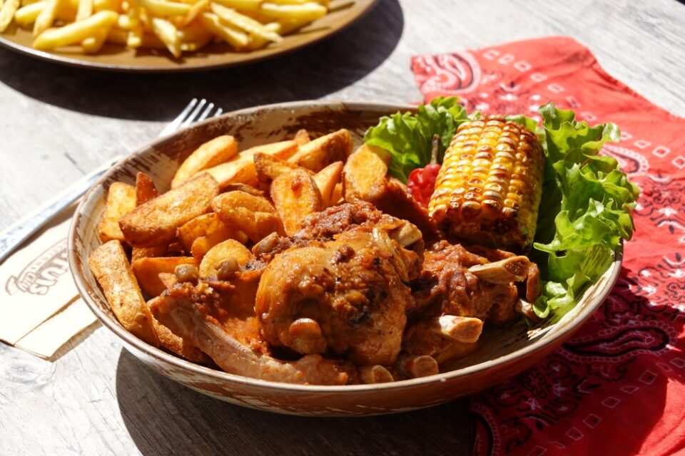 Menu Cowboy avec pilon de poulet, maïs, travers de porc et potatoes, servi dans le restaurant Le Saloon à Fraispertuis-City